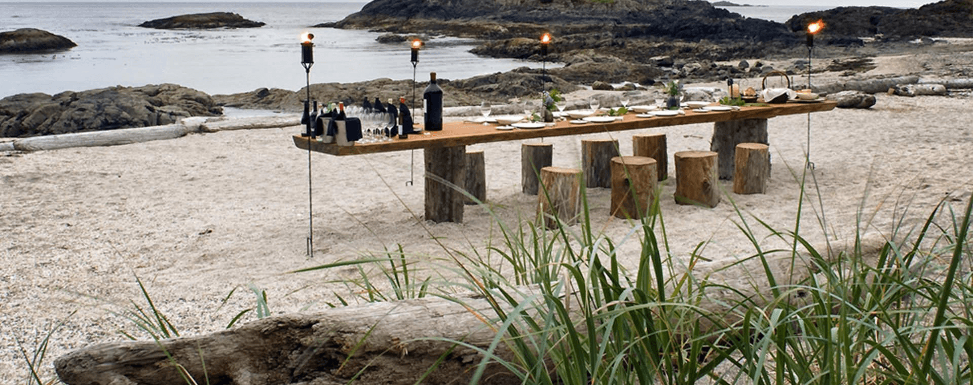 table on the beach set for dinner with wine