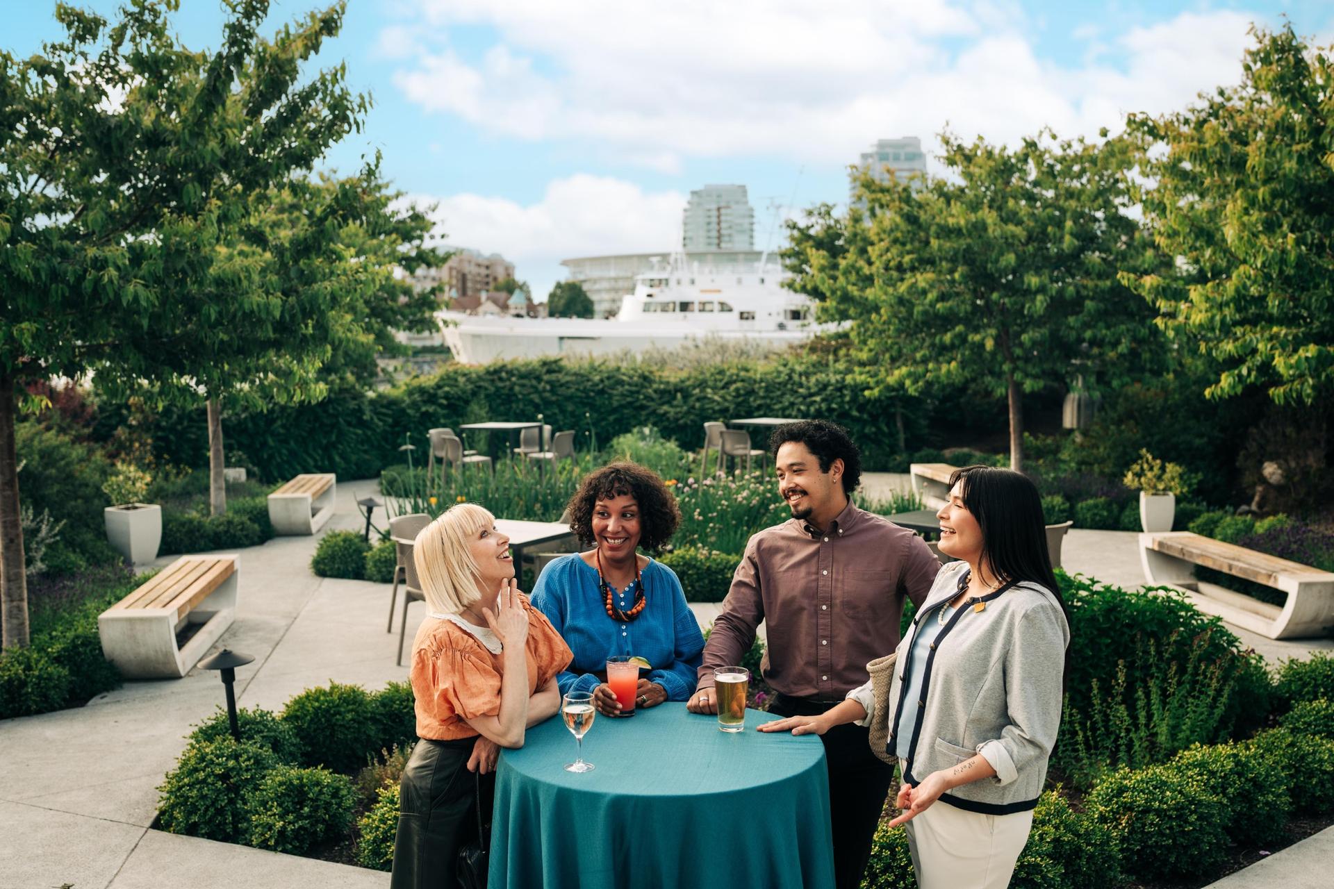 Delegates have a discussion outside the Inn at Laurel Point while the BlackBall Ferry Lines Coho Ferry passes in the background
